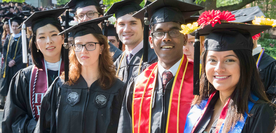 Group of graduating students wearing caps and gowns and smiling at the camera