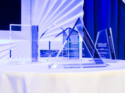 Photo of the glass Alumni Association Awards (5 total) lit up on the stage during the Homecoming Luncheon