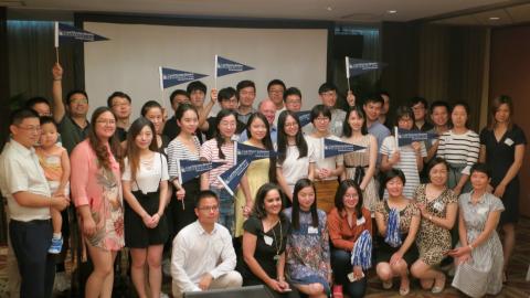 Group of incoming CWRU students, posed and smiling for the camera, waving CWRU pennant flags