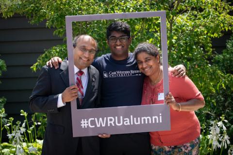 Two parents and a college-aged son pose in a frame that says #CWRUalumni