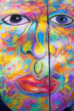 A close-up view of the chalk portrait with bright red lips and swirls of green, blue, yellow, pink, orange and purple all over the face