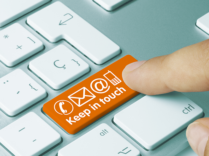 Photo of a hand pushing a key on a keyboard that says "Keep in Touch"