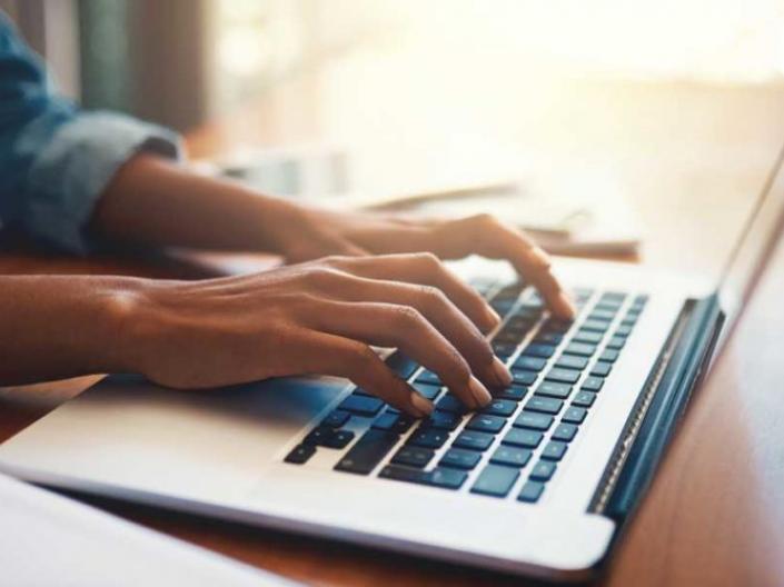 A person's hands typing a laptop keyboard