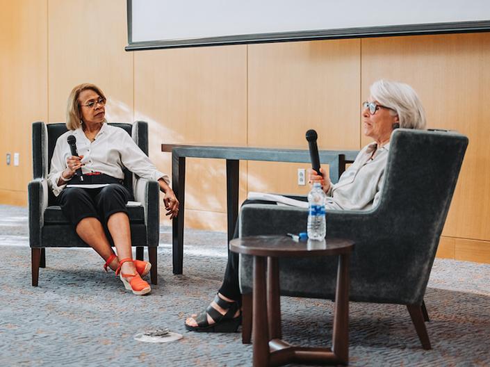 Two women sit onstage for a panel discussion