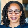 Ayesha Bell Hardaway wears hoop earrings and glasses, smiling at the camera