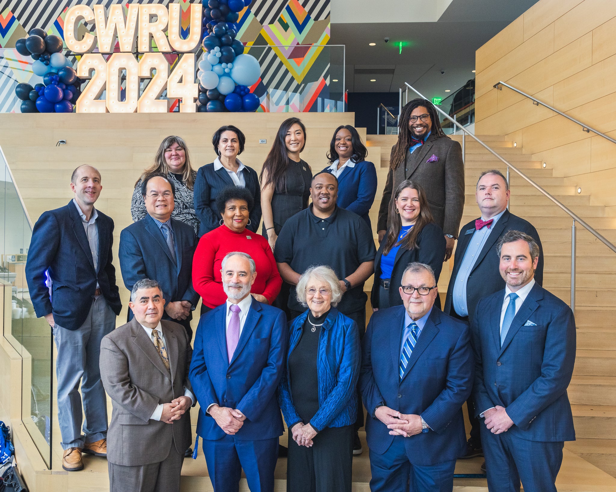 CWRU Alumni Board smile in front of camera as a group, with illuminated "CWRU 2024" sculpture and multicolored mural behind them