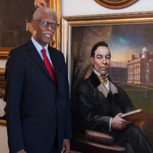 David Johnson, in a blue suit, stands next to the newly unveiled portrait of John Sykes Fayette