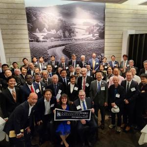 Members of the Japan Chapter of the Alumni Association of CWRU smile for camera with a CWRU banner at the front of the group