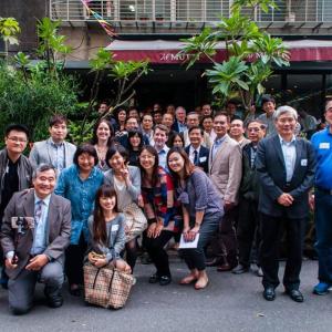 Members of the Taiwan Chapter of the Alumni Association of CWRU smile for the camera as a group in front of plants and a business
