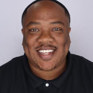 Donté Gibbs smiles at camera while wearing a collared shirt