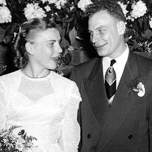 Black and white photograph of a couple smiling at each other on their wedding day, wearing formal wedding attire