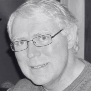 Michael Magness smiles at camera while wearing glasses