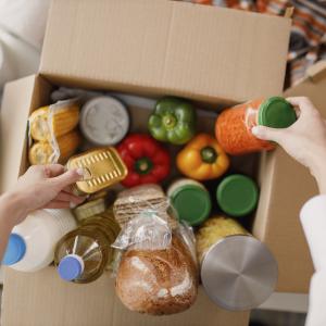 Stock image of a person's hands which are sorting through a box of donated food products