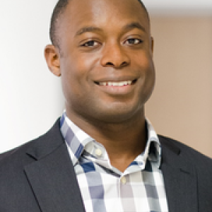 Sam Senyo smiles at camera while wearing formal attire