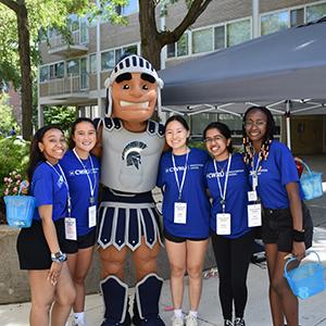 Students smile at camera next to Spartie mascot