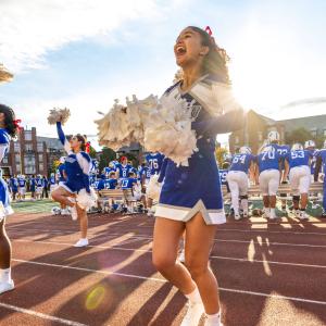 CWRU cheerleaders perform on football sidelines in the daytime