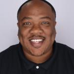 Donté Gibbs smiles at camera while wearing a collared shirt