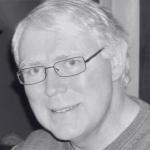 Michael Magness smiles at camera while wearing glasses