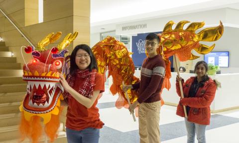 Three CWRU international students pose with the dragon from the 2018 Lunar New Year celebration