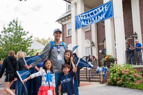 Photo of Arnold Huffman and his children, posed and smiling wearing CWRU gear outside of the Linsalata Alumni Center