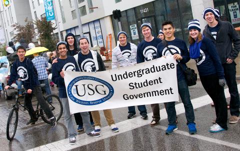A group of USG students march in the Homecoming parade behind a USG banner