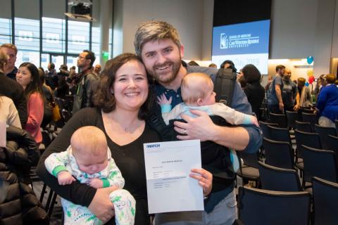 A couple holds children and their match letter during CWRU Match day 2019