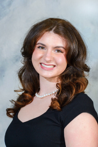 Cassidy Lyninger smiles at camera in front of a gray background while wearing a black shirt