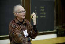 Don Knuth stands in front of the blackboard in a lecture hall