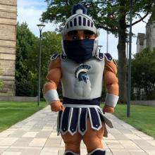 Case Western Reserve University mascot Spartie stands on the Binary Walkway wearing a facemask