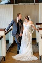 Couple smiles at each other in wedding attire, facing each other