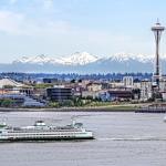 Passenger boat passes through Puget Sound in front of the Seattle skyline during the day