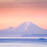 Ferry passes through Puget Sound at sunrise in front of Mount Rainier