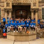 Hudson Relays alumni team poses in team T shirts in front of Adelbert Hall