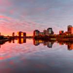 View of Newark, New Jersey, skyline near the water in the evening, with a red-tinted sky above and reflected in the water