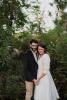 Couple smiles at each other in wedding attire, embracing each other