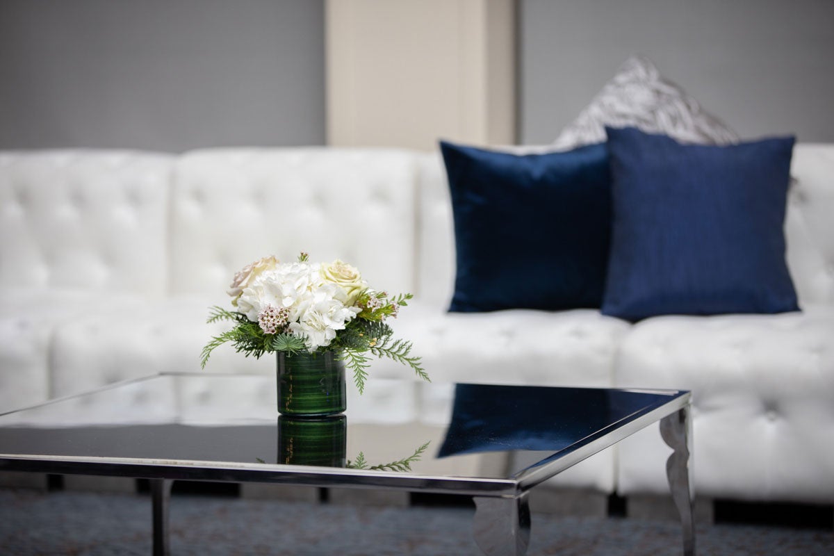 A table setting with white flowers for an event in the Great Hall at the The Linsalata Alumni Center