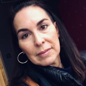 headshot of white woman with long dark hair and silver hoop earrings