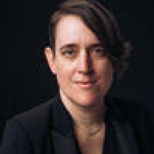 Headshot of white woman with dark hair and a dark shirt