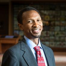 Color head shot of african american man (Sylvester Johnson) in a library wearing suit and tie