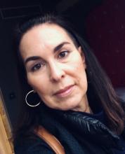 headshot of white woman with long dark hair and silver hoop earrings