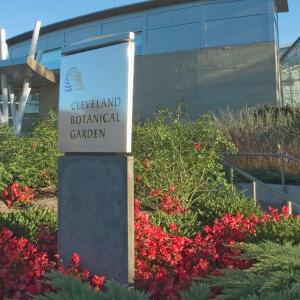 Color image of Cleveland Botanical Garden building and sign with red flowers and lots of greenery in front