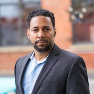 Image of African American Man in blazer standing outside in front of a building