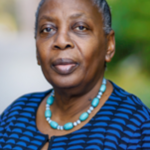 Image of African American woman with her hair pulled back wearing a blue necklace and jacket.