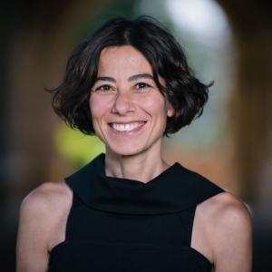 Image of smiling white woman with bobbed brown hair wearing a sleeveless black top