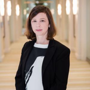 Color photo of woman with shoulder length brown hair wearing a black and white top