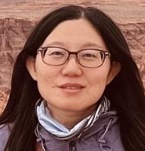 Headshot of Asian woman with long dark hair parted in the middle wearing glasses