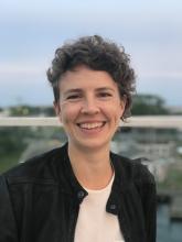 Headshot of smiling white woman with short curly brown hair outside