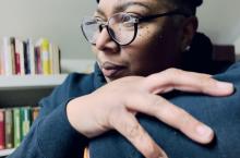 Side profile of woman with glasses and hand on her own shoulder
