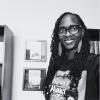 black and white photo of smiling black woman with long hair, glasses, and large dangly earrings