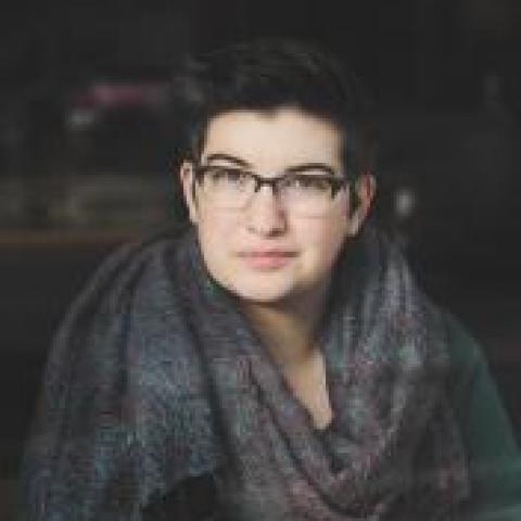 White person with glasses and short dark hair wearing shawl around their neck
